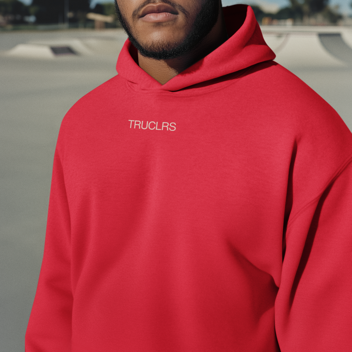 Person wearing a red hoodie with 'TRUCLS' logo outdoors