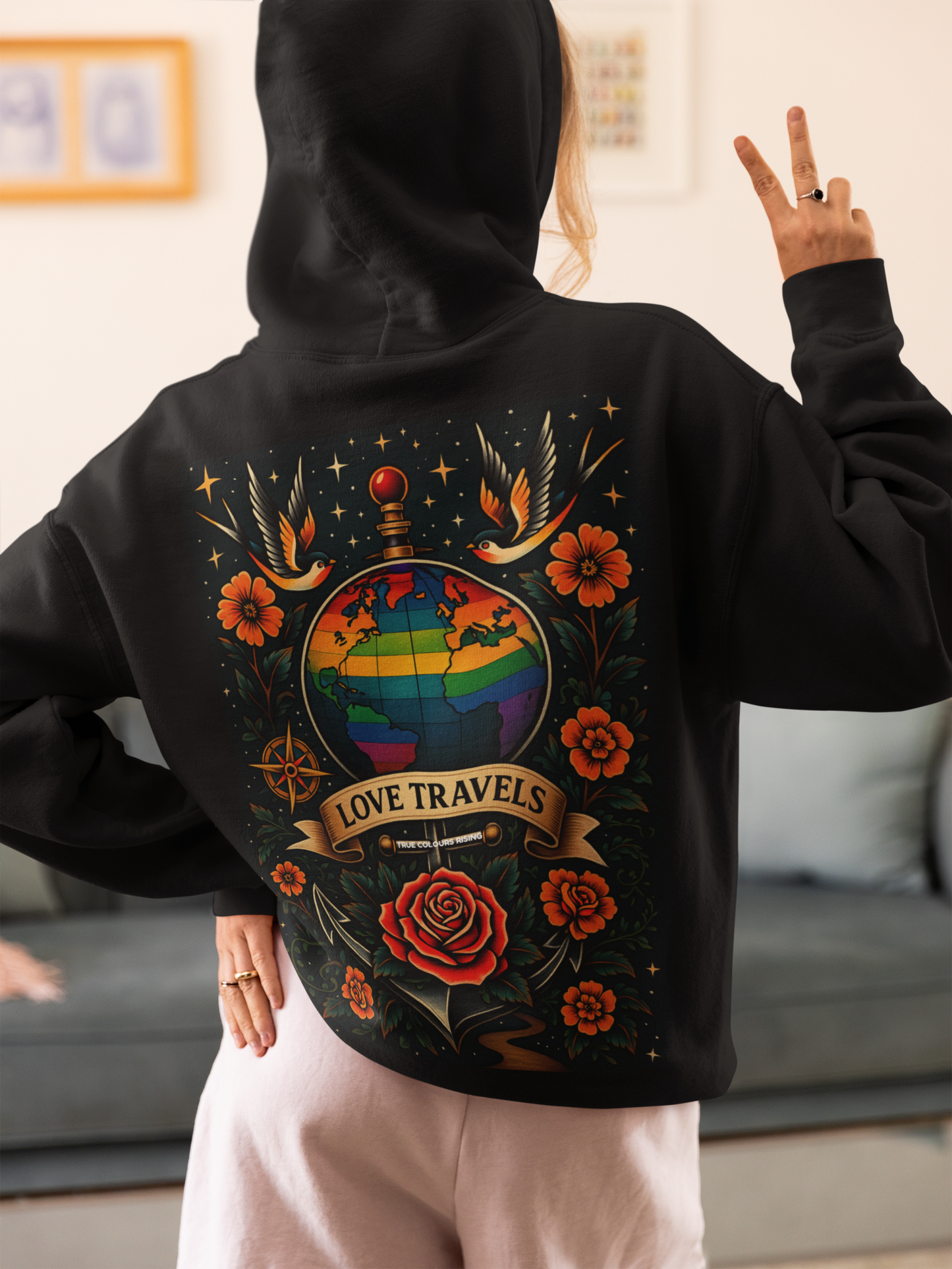 Queer pride hoodie featuring rainbow world globe design and banner reading Love Travels
