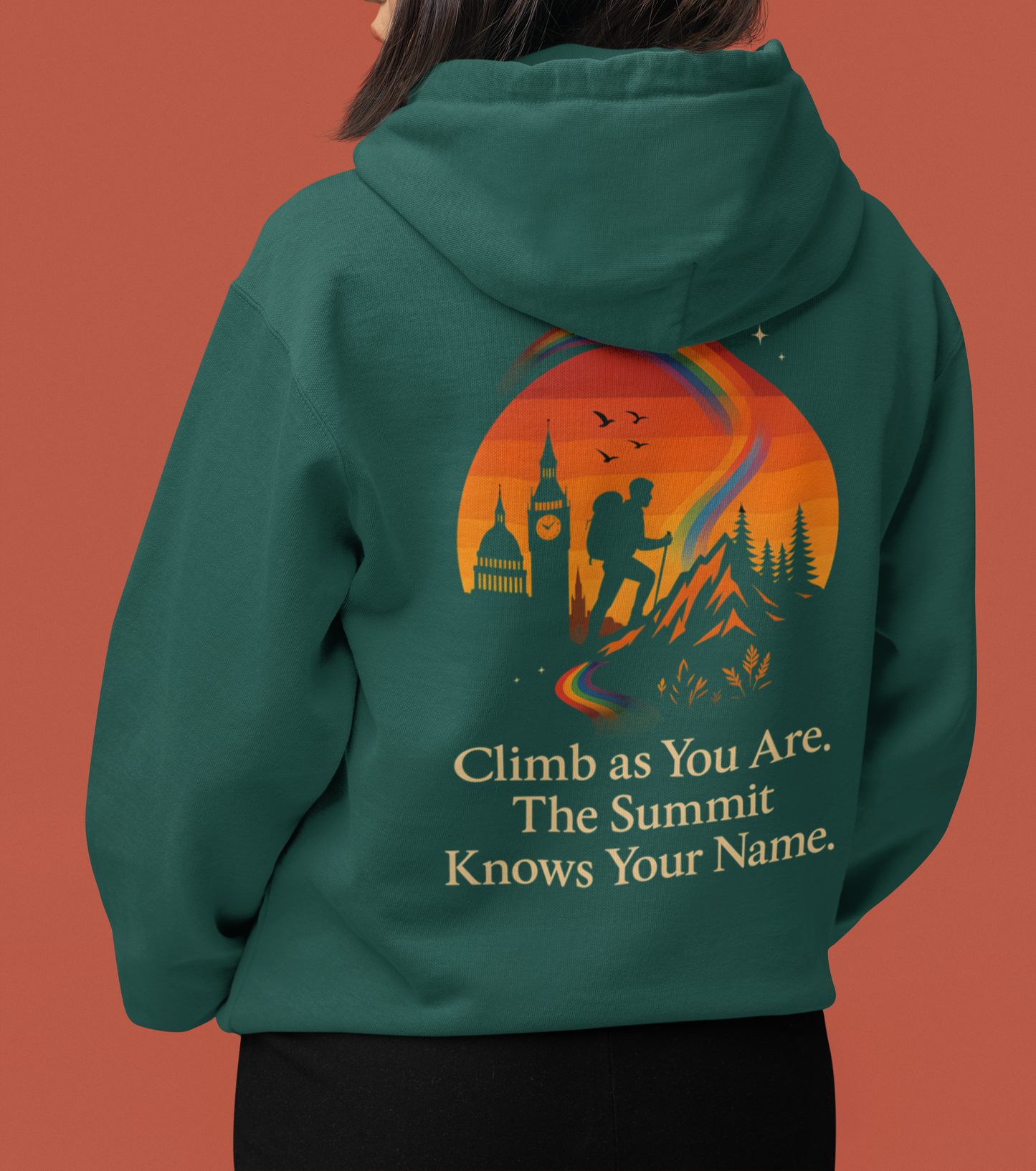 Queer pride hiking hoodie featuring mountain silhouette, rainbow path, and motivational summit quote