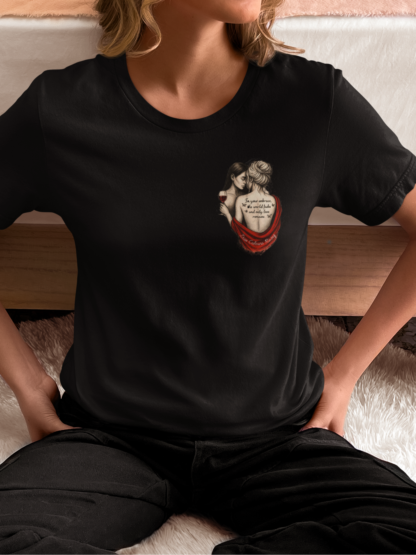Artistic photo of a woman in a black t-shirt with a tattoo-style graphic of a queer femme couple on the front