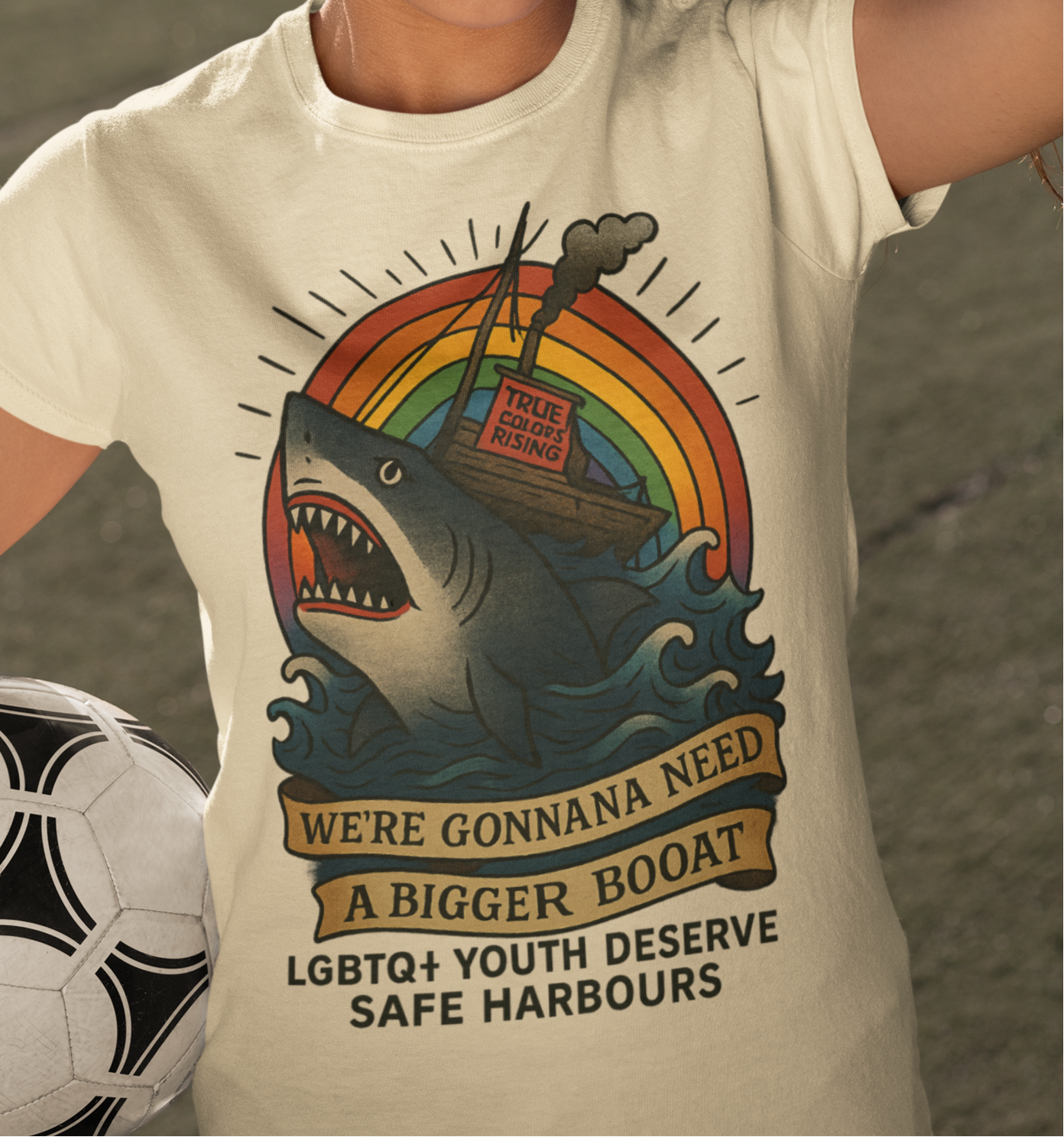 Person wearing a t-shirt with a shark graphic and text on a sports field. Jaws Quote. LGBTQ+