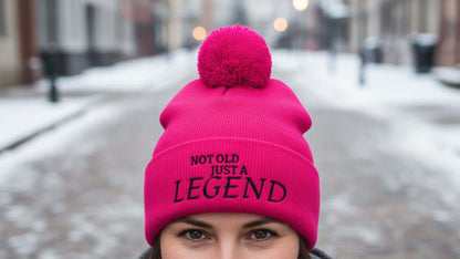 Pink beanie with pom-pom and 'Not Old Just a Legend' text on a white background