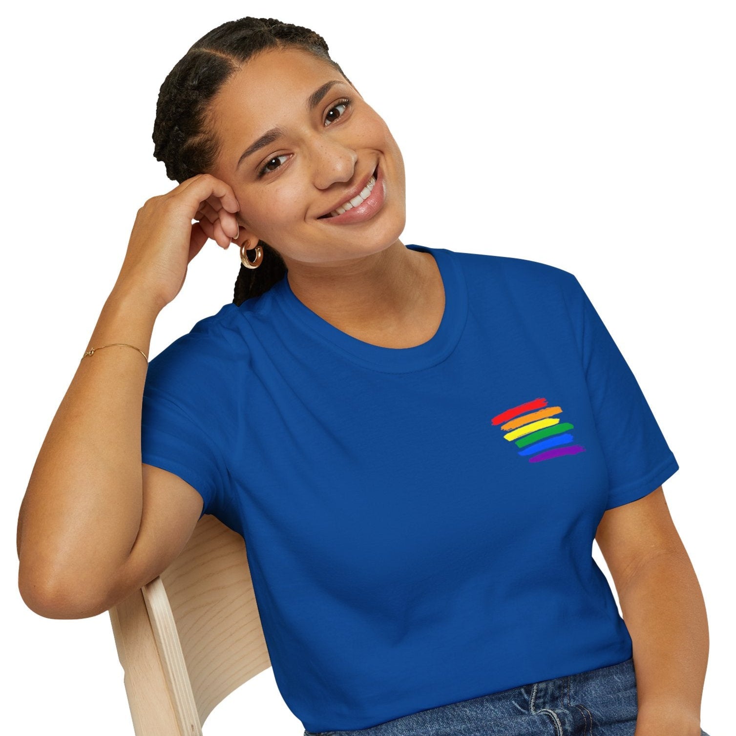 Smiling woman in blue True Colours Rising rainbow pride t-shirt with colored stripes, promoting equality and style.