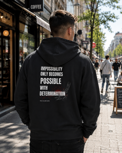 Back view of IMPOSSIBILITY BECOMES POSSIBLE WITH DETERMINATION premium black hoodie featuring a bold motivational typography print with broken chain artwork.