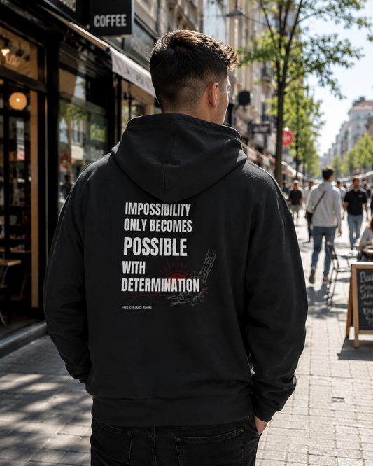 Back view of IMPOSSIBILITY BECOMES POSSIBLE WITH DETERMINATION premium black hoodie featuring a bold motivational typography print with broken chain artwork.
