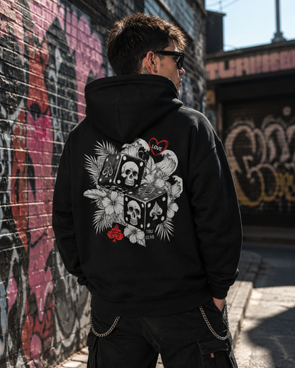 Back view of the Love Is a Gamble hoodie showing the skull dice graphic while waiting at a London bus stop.