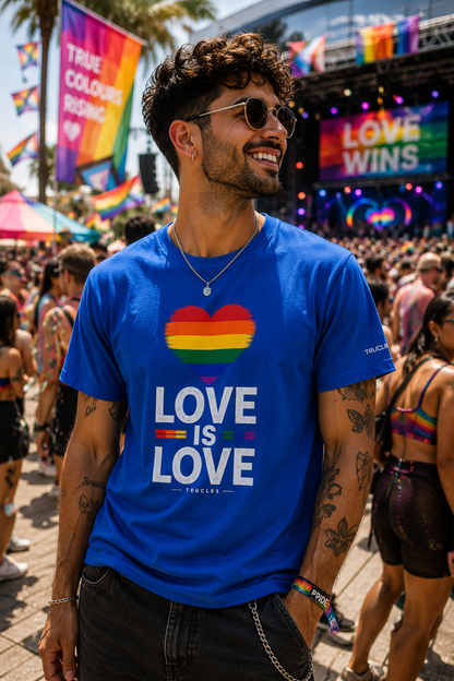 Man wearing Love Is Love Pride T-Shirt with rainbow heart at a lively LGBTQ+ festival celebrating love and self-expression.