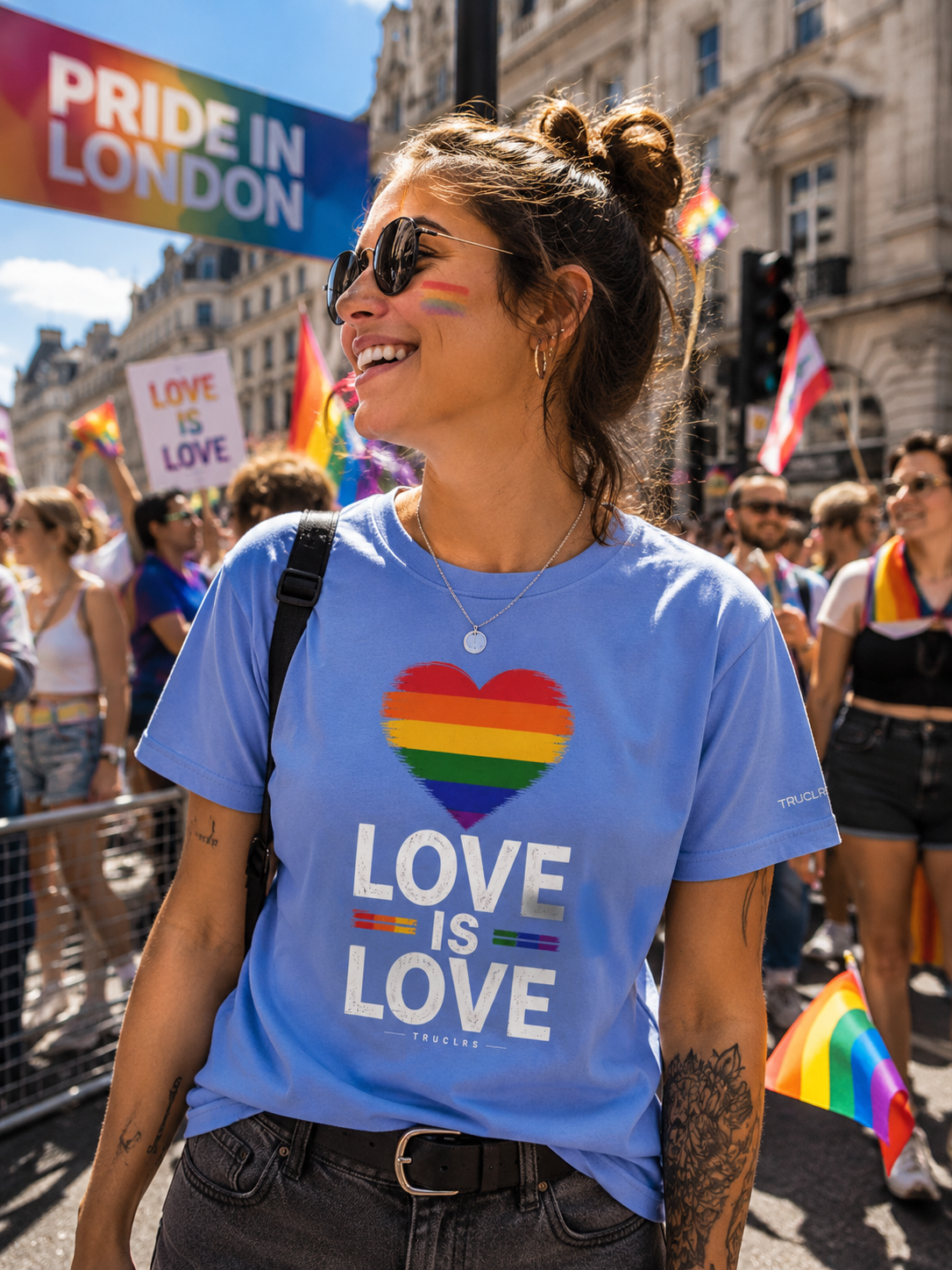 Person smiling at Pride event wearing Love Is Love Pride T-Shirt with rainbow heart design.