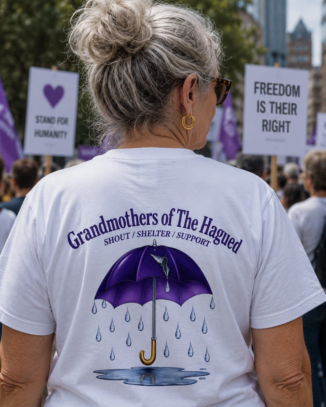 Person wearing a white t-shirt with 'Grandmothers of the Hagued' design and text at a protest event.