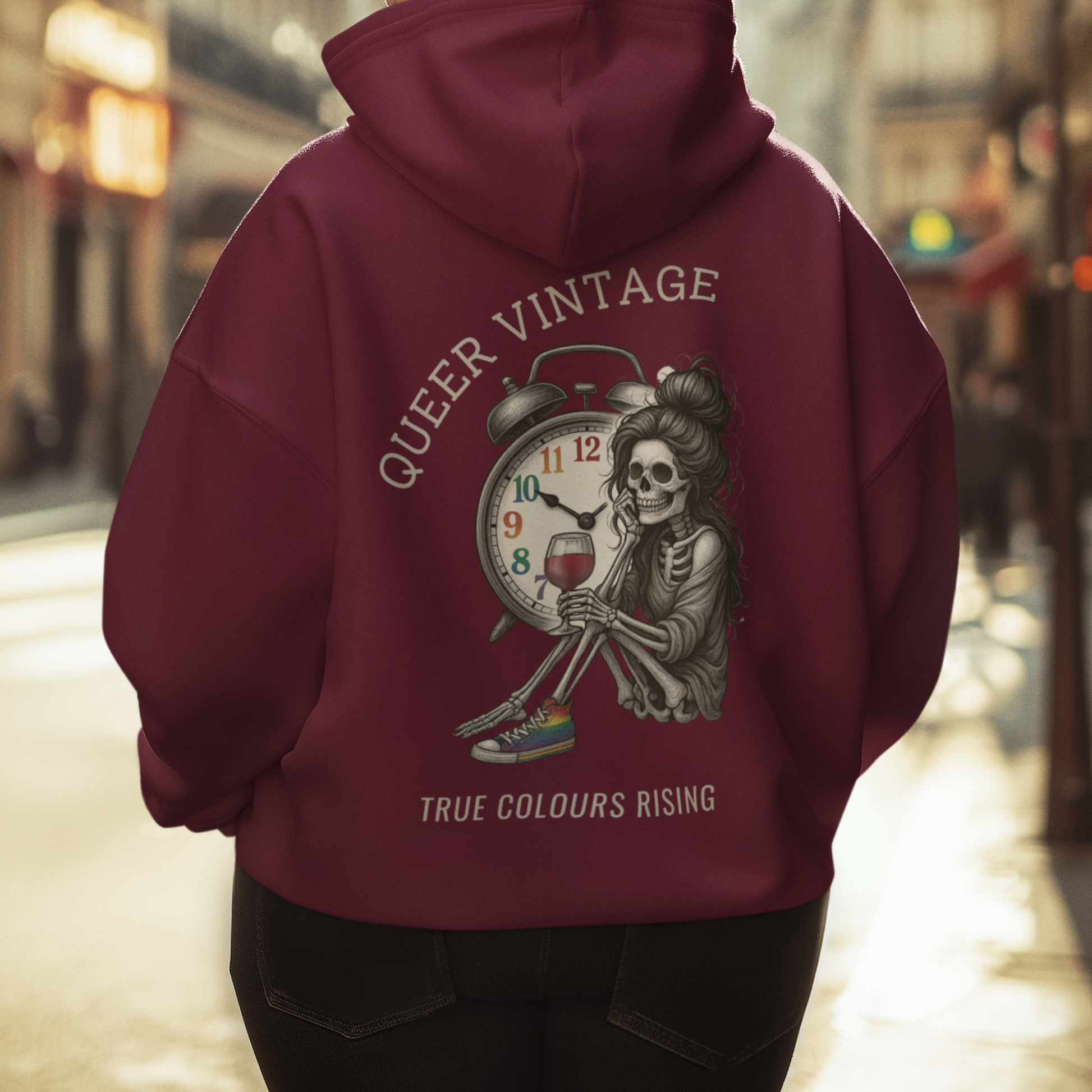 Queer Vintage -True Colours Rising Skeleton Clock Hoodie showing skeleton holding wine glass beneath rainbow clock design