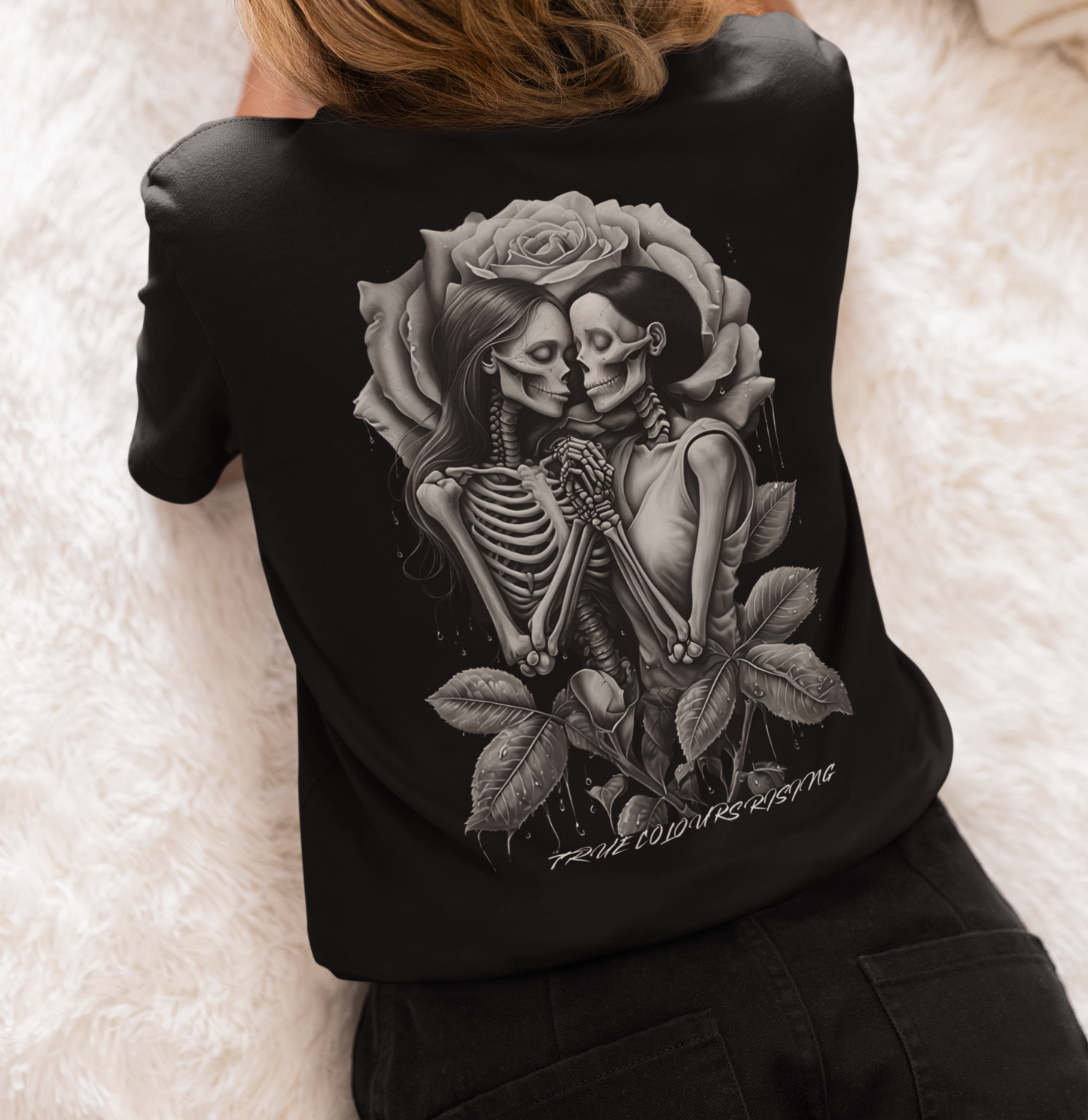 Back view of black T-shirt featuring two skeletons holding hands framed by a rose

Close-up of skeleton couple tattoo-style artwork on True Love Never Dies tee
