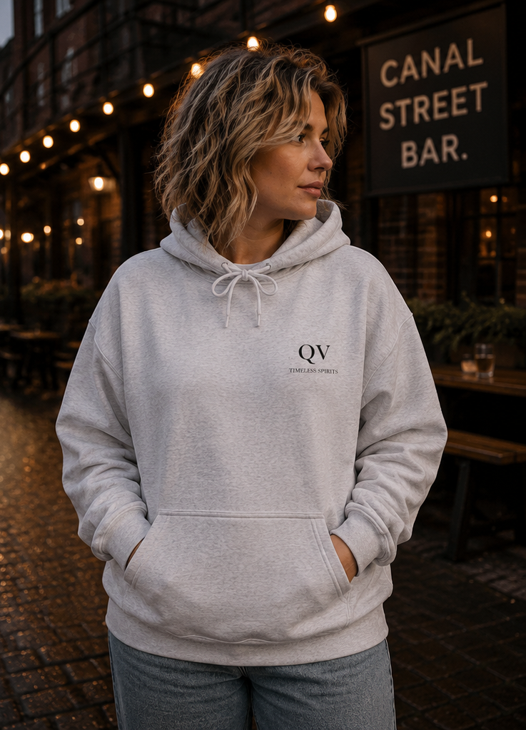 Woman modelling a gender-inclusive hoodie in an urban UK setting at dusk.